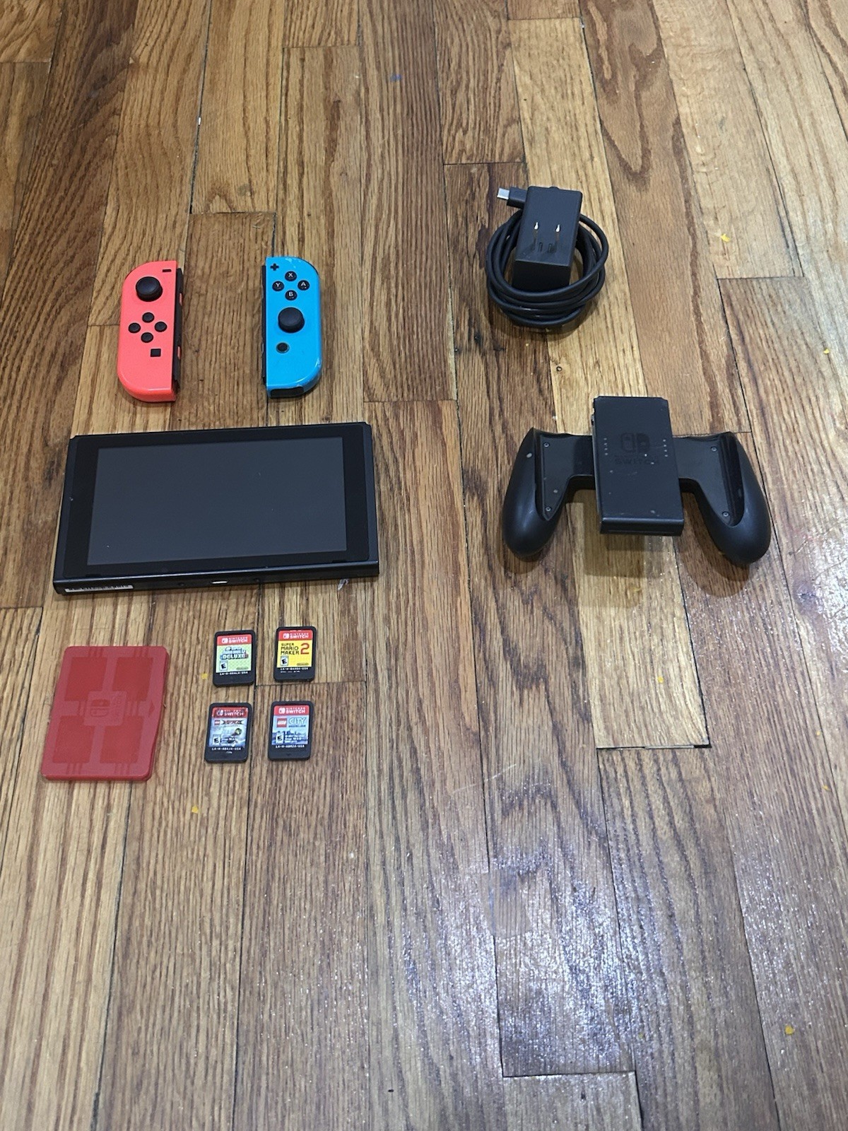 Nintendo Switch with joycon controllers, a charger, 4 games, and a game case.